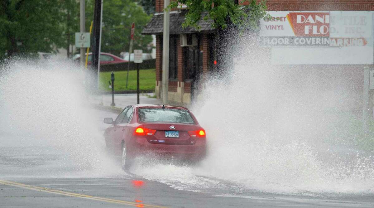 A car splashes through water on Main Street in Danbury. Part of the street was blocked off because of water from Tropical Storm Elsa.