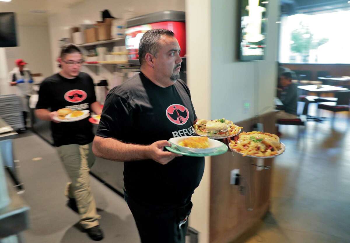 Wait staff bring orders to diners at Refuge in San Mateo, where a new “wellness” fee is covering increased labor costs.