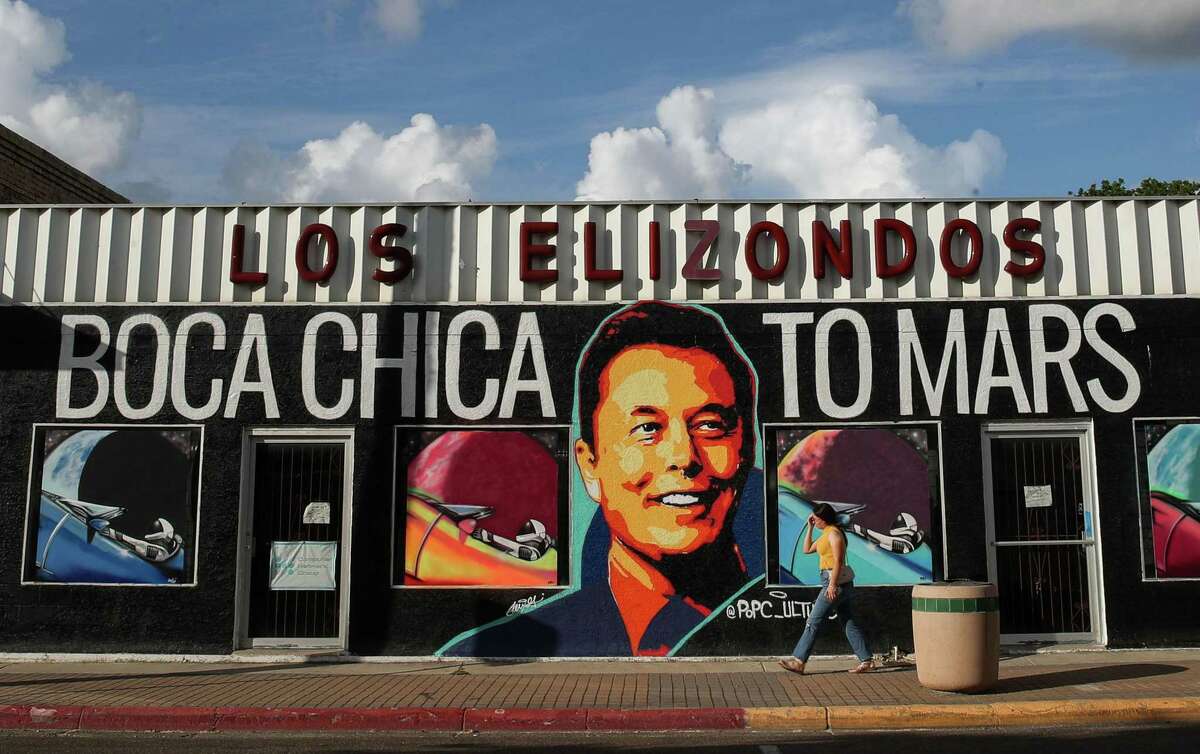 A woman walks by a mural featuring SpaceX founder Elon Musk that is promoting an art exhibit titled “Boca Chica to Mars,” on Wednesday, June 16, 2021, in Brownsville. SpaceX has been building launch facilities in Boca Chica, an unincorporated area near the city.