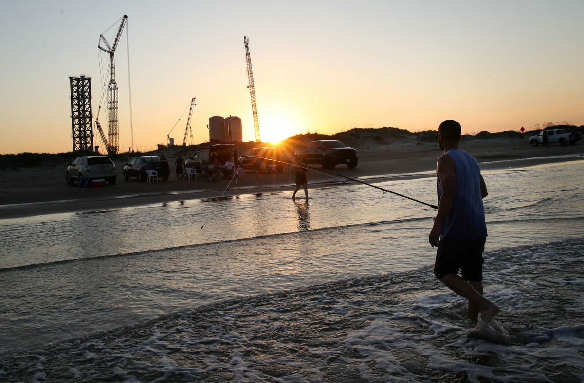 Joe Carrizales fishes with family as construction of the SpaceX launch facility continues in the background Monday, June 14, 2021, in Boca Chica.