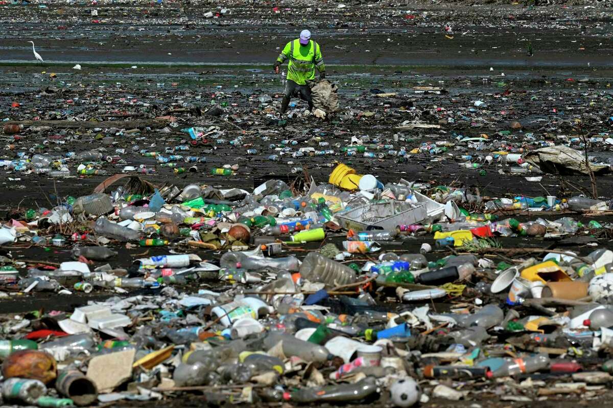 A man collects garbage, including plastic waste, at the beach of Costa del Este, in Panama City, on April 19, 2021. (Luis Acosta/AFP/Getty Images/TNS)