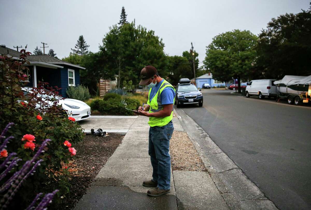 Utility system operator Shiloh Jones writes a notice to a resident not adhering to water restrictions in Santa Rosa. Jones patrols neighborhoods giving notice to residents about city water restrictions.