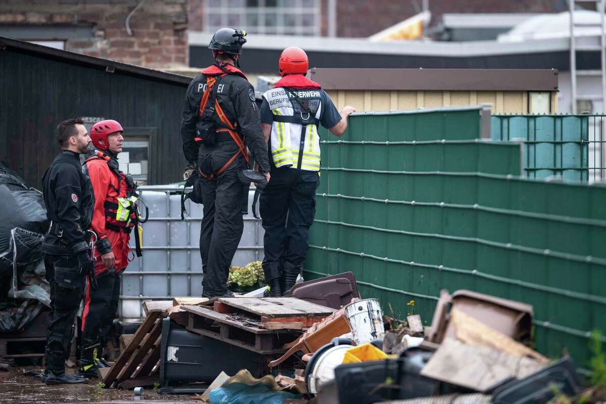 Police and fire brigade personnel stay at a fence in the Blessem district of Erftstadt, Germany, Friday, July 16, 2021. Heavy rains caused mudslides and flooding in the western part of Germany. Multiple have died and dozens are missing as severe flooding in Germany and Belgium turned streams and streets into raging, debris-filled torrents that swept away cars and toppled houses. (Marius Becker/dpa via AP)