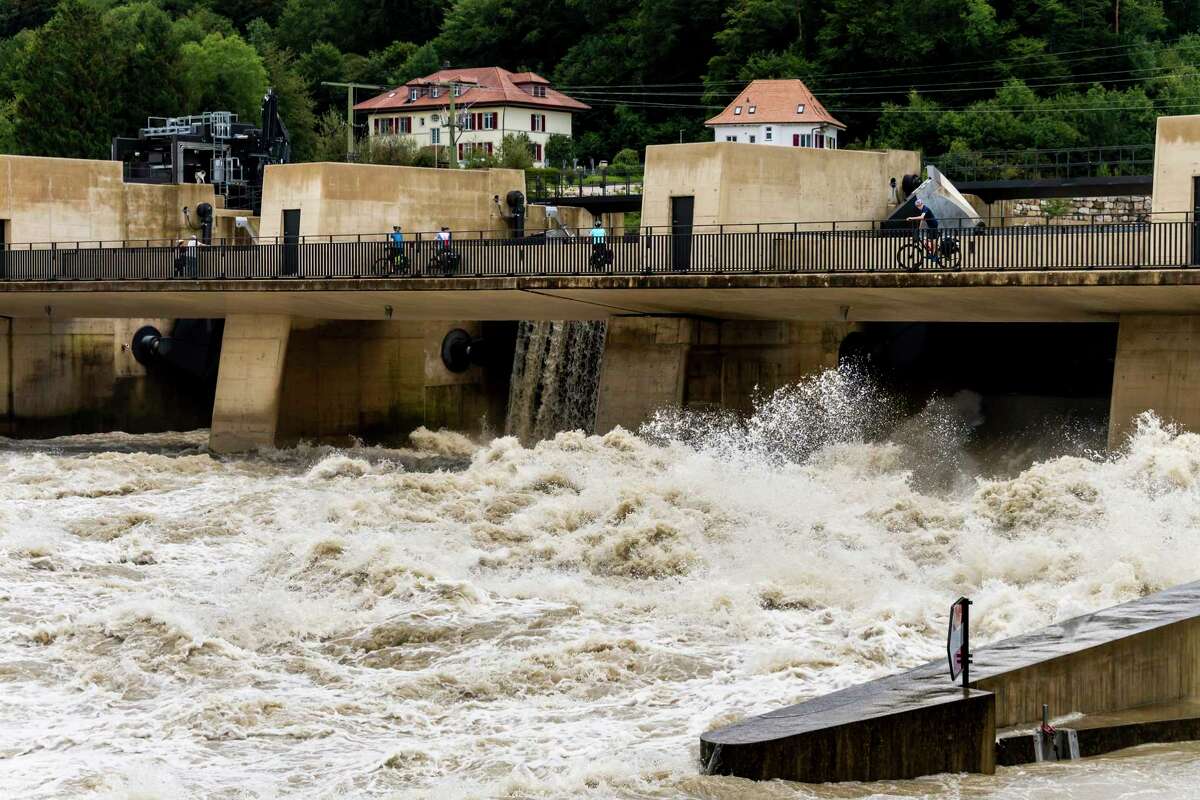 Water flows through the Hagneck dam between the Aare and the Bielersee in Hagneck, Switzerland, Friday, July 16, 2021. The water level of the Bielersee continued to rise throughout the night, exceeding the flood level by 45 centimeters on Friday morning. Since Monday, the level has risen by 1.2 meters. The lake could reach a record height during the day. (Jean-Christophe Bott/Keystone via AP)