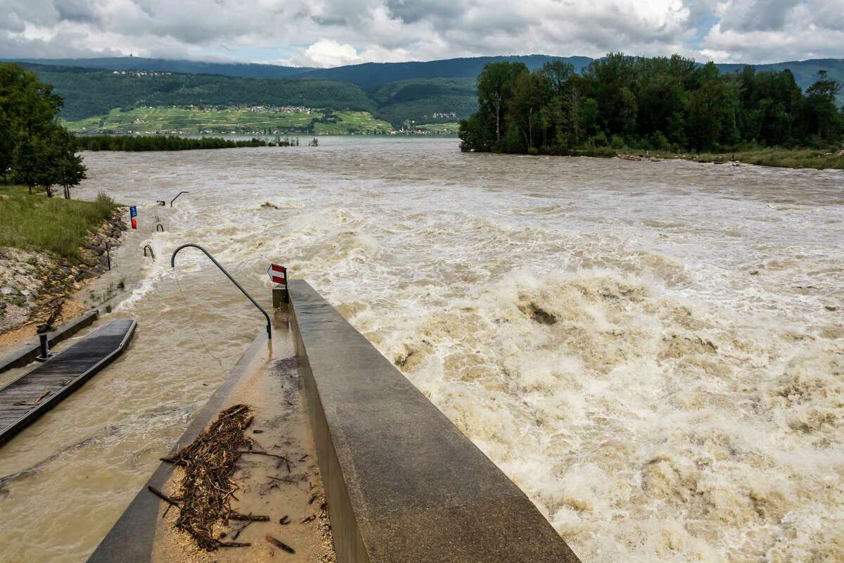 Water flows through the Hagneck dam between the Aare and the Bielersee in Hagneck, Switzerland, Friday, July 16, 2021. The water level of the Bielersee continued to rise throughout the night, exceeding the flood level by 45 centimeters on Friday morning. Since Monday, the level has risen by 1.2 meters. The lake could reach a record height during the day. (Jean-Christophe Bott/Keystone via AP)