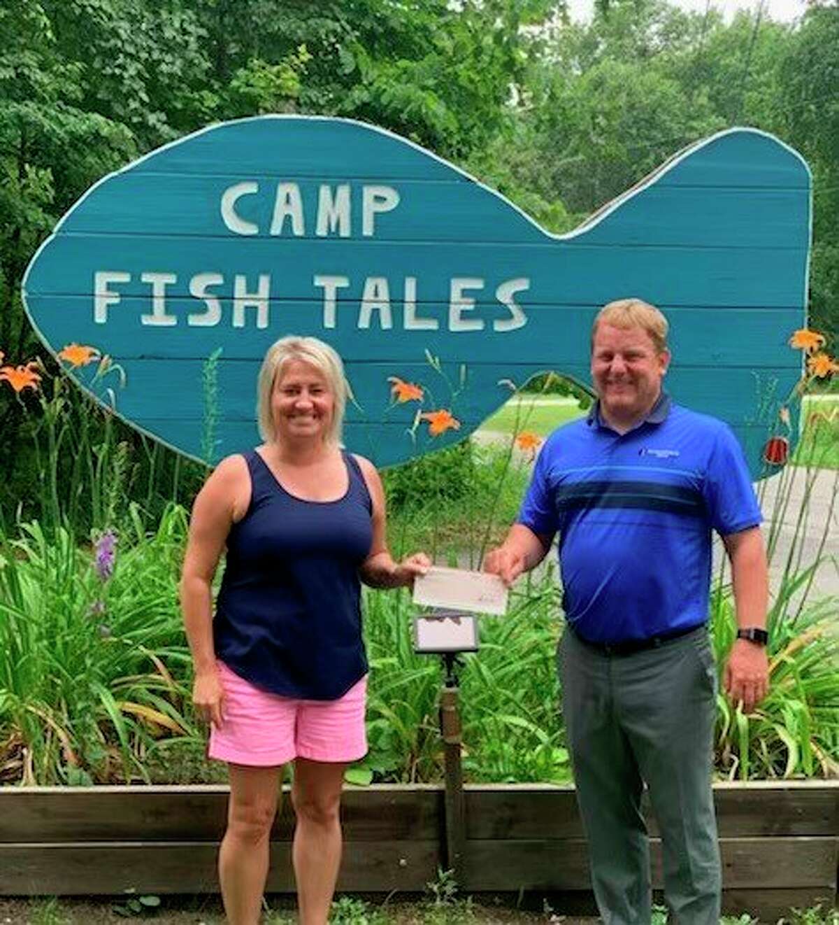 Shannon Forshee, executive director at Camp Fish Tales receives a check for $4,000 from Karl Ieuter from Ieuter Insurance Group. (Photo provided)  