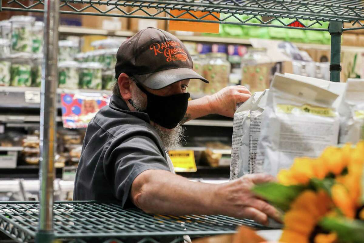A Rainbow Grocery employee stocks a shelf with pancake mix in San Francisco in June. Masks are required in indoor public settings in San Francisco.