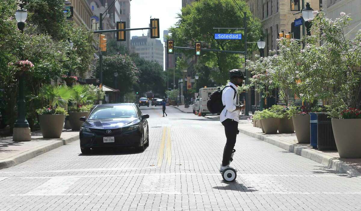 Terry French, founder and CEO of social networking company WXYZr, rides across Houston Street on a hoverbot.