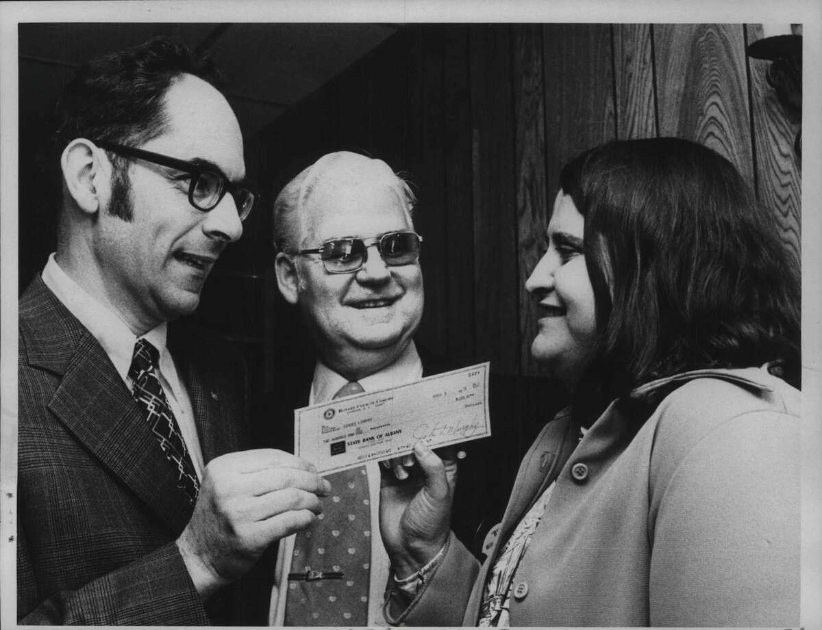 (From left) R. Mihran Mooradian, President of Cohoes Rotary Club, William J Dillon, program chair, and Carol Clingan, chief librarian at Cohoes Public Library, receives check for $200 from the Cohoes Rotary Club at dinner at Mac's Restaurant in Cohoes, New York. April 17, 1975 (Bob Richey/Times Union Archive)