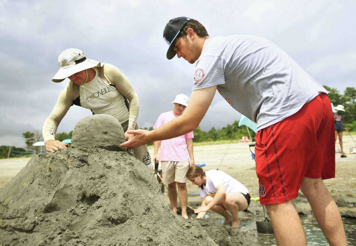 Milford Robotic Club leader Chris Seluga, left, and club member Joe Gaetano, 16, of Milford, sculpt the head of their Lego person riding a paddle board sand sculpture during the annual sand sculpture competition at Walnut Beach in Milford Conn. on Sunday, July 18, 2021. Live judging was cancelled for fear of rain, but contestants were still able to submit photographs of their finished sculptures for judging in a virtual competition.