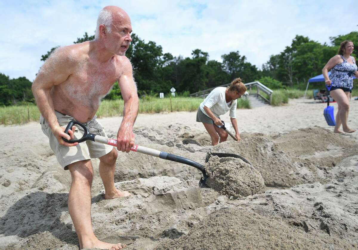 Fom left; Chris Lee, of Fairfield, Maria Bruno, of Milford, and Elise Lee, of Milford, dig in during the annual sand sculpture competition at Walnut Beach in Milford Conn. on Sunday, July 18, 2021. Live judging was cancelled for fearr of rain, but contestants were still able to submit photographs of their finished sculptures for judging in a virtual competition.