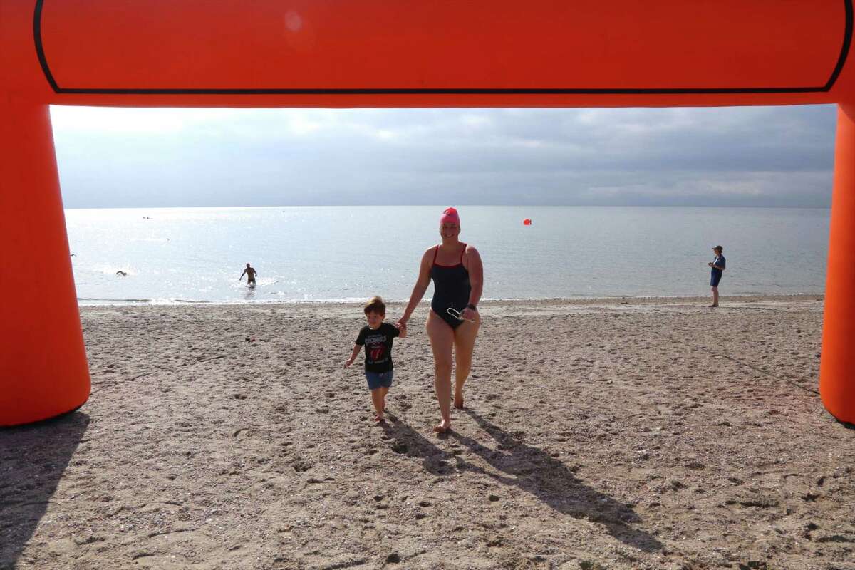 Ashley Fedor of Weston walks through the finish arch with her son Mateo Llaza, 2, at the Point to Point Swim at Compo Beach on Sunday, July 18, 2021, in Westport, Conn. "I'm really excited," said Josephine Rojas, the Y's new aquatics director, who was seeing it for the first time. "The rain seems to be staying off," she said before the start. "It's a balmy morning, but it's great for swimming." Many agreed, but also noted that any open water swim can present some subtle challenges for long distances.
