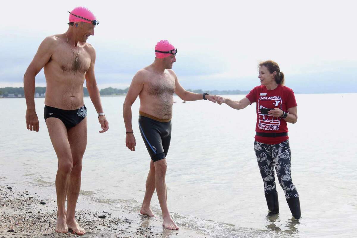 Denise Hotch, fitness coordinator at the Y, gives encouragement to some swimmers before the race at the Point to Point Swim at Compo Beach on Sunday, July 18, 2021, in Westport, Conn. "What a race like this does is it separates a lot of swimmers," explained Gregory Sargent of Fairfield, who showed the fastest time of the day with 12 minutes and eight seconds. He explained how the current was moving with the swimmers after they rounded the first buoy, where he said a lengthy stroke worked best to move with the tide.