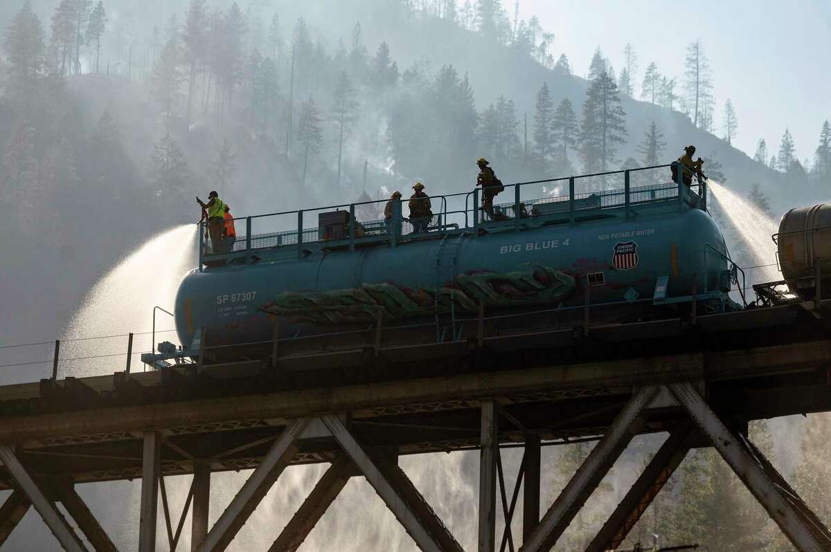 Firefighters spray water from Union Pacific Railroad’s fire train while battling the Dixie Fire in Plumas National Forest on Friday.
