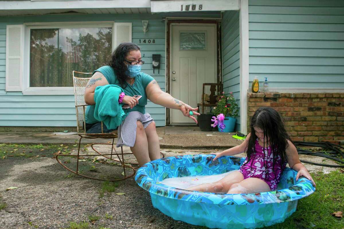 Diana Gonzalez sits outside her house watching her daughter, Maddilyn, play in her baby pool Monday in Galena Park