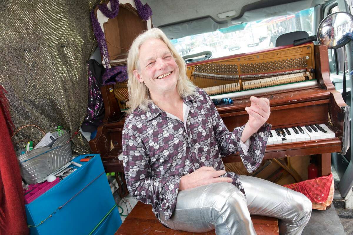 Brandy Collins, whose name is Mr. Brandy, pretends to play air guitar in his Sprinter van in the Haight-Ashbury neighborhood of San Francisco on July 16, 2021.