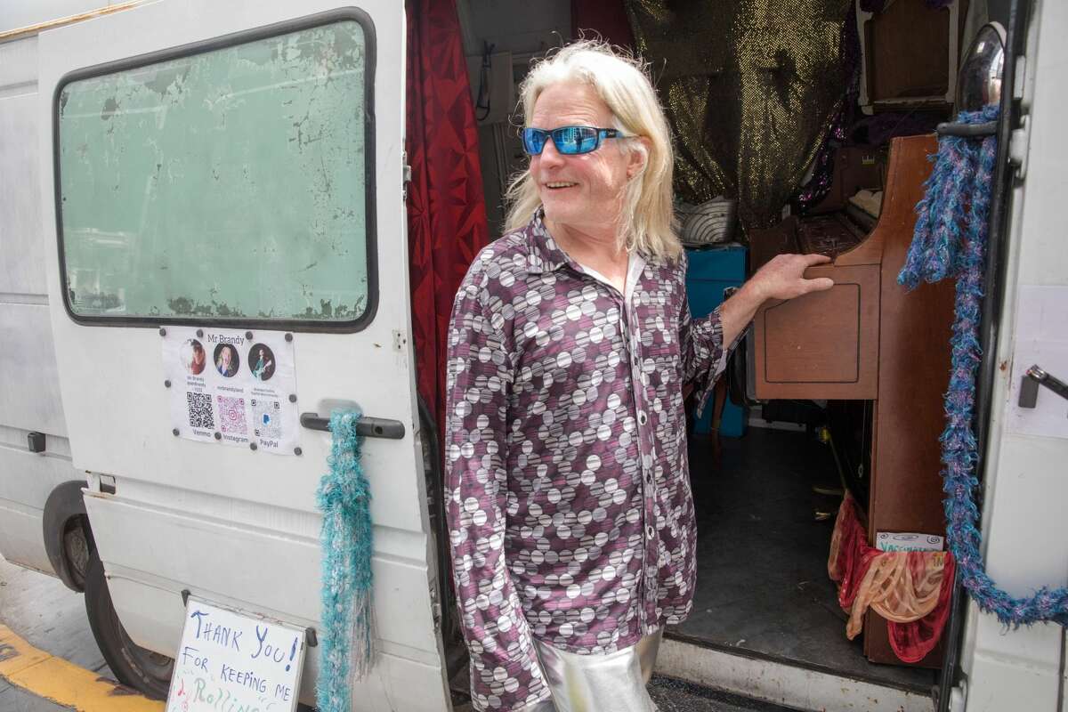 Brandy Collins, whose performance name is Mr. Brandy, takes a break from playing the piano inside the back of his Sprinter van in the Haight-Ashbury neighborhood of San Francisco on July 16, 2021.