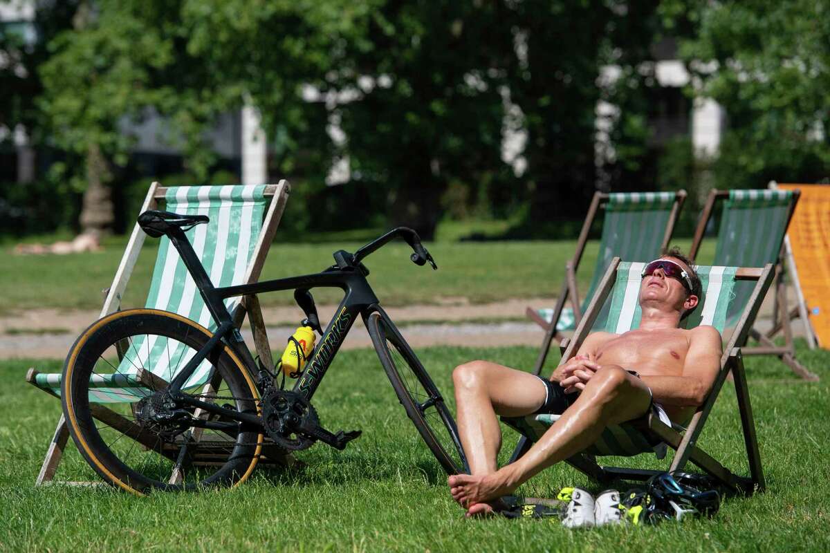 A man relaxes in the morning sunshine during a spell of hot weather in Green Park central London, Tuesday July 20, 2021. Temperatures are set to soar to sweltering highs this week according to weather forecasts, and the Met Office issued an unprecedented heat warning. (Dominic Lipinski/PA via AP)