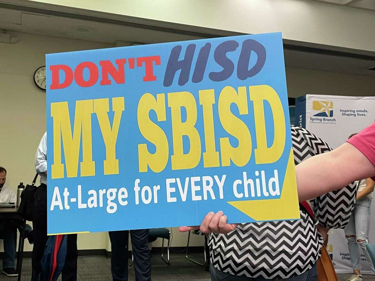 A member of the audience for the Spring Branch ISD special board meeting on July 19 holds a sign to send a message to the board members about the lawsuit referencing at-large vs. single-member district board elections.