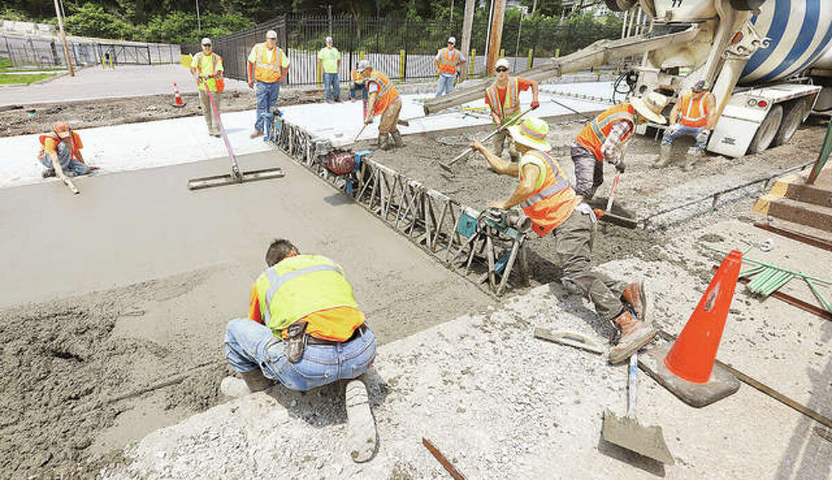 Construction workers lay fresh concrete on Williams Street in downtown Alton Tuesday. The street will eventually get its historic bricks placed back on top of the concrete. The Williams Street work is among a collection of city projects bringing improvements to all seven of the city’s wards.