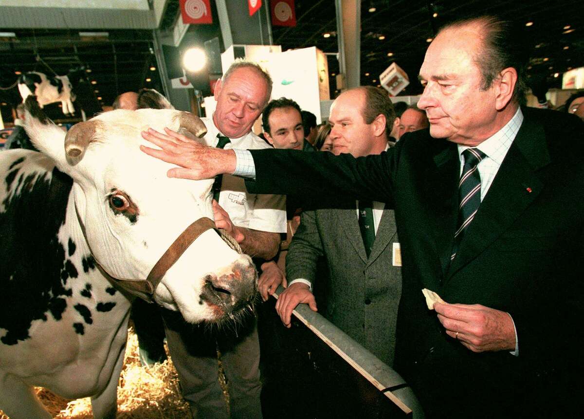 French President Jacques Chirac pets a cow while eating a piece of cheese as he inaugurates the 35th Agriculture Fair in Paris Sunday March 1, 1998.
