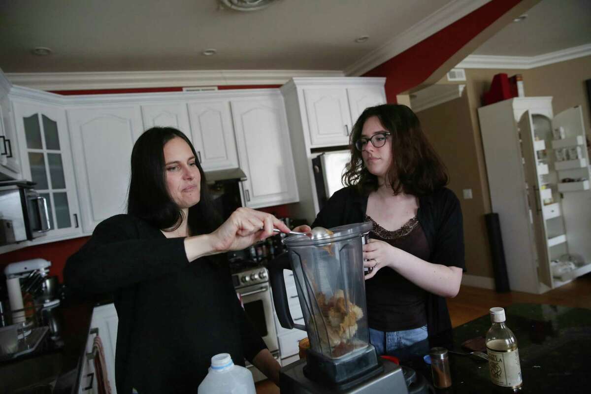 Sarah Feldstein (left) helps her daughter, Maya Korenman, make a smoothie in the kitchen of their home. Feldstein was fully vaccinated when she developed symptoms in early June and then tested positive for the coronavirus.