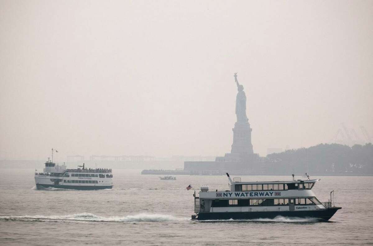 The Statue of Liberty sits behind a cloud of haze in New York City on Tuesday, with wildfire smoke from the West arriving in the region.