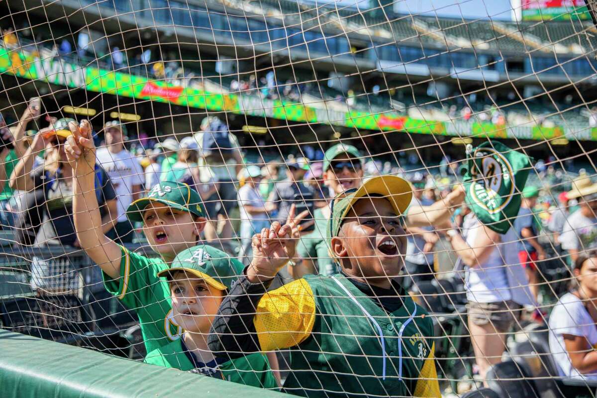 From left: Devon Fischer, 9, Dillon Fischer, 7, and Javaughn Thomas, 8, try to get the attention of Stomper, the Oakland Athletics’ mascot following the MLB game between the A’s and the Los Angeles Angels at RingCentral Coliseum on Tuesday, July 20, 2021, in Oakland, Calif. The A’s won 6-0.