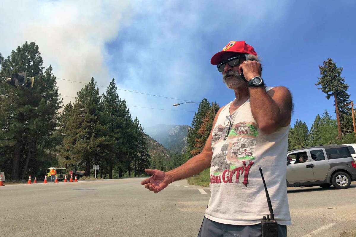 Tony Galvez, who lost his home to the Tamarack Fire, talks on his phone with his daughter in Vermont who's setting up a GoFundMe for him as he waved and clapped at passing firefighters in Woodfords, Calif., on Tuesday, July 20, 2021. In Northern California, authorities expanded evacuations for the Tamarack Fire in Alpine County in the Sierra Nevada to include the mountain town of Mesa Vista late Monday. That fire, which exploded over the weekend was 61 square miles (158 square kilometers) with no containment.