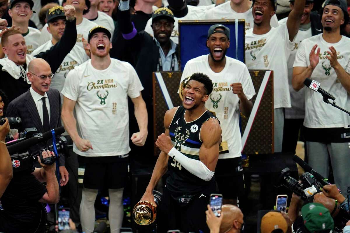 Milwaukee Bucks forward Giannis Antetokounmpo (34) reads with the championship trophy after defeating the Phoenix Suns in Game 6 of basketball's NBA Finals in Milwaukee, Tuesday, July 20, 2021. The Bucks won 105-98.