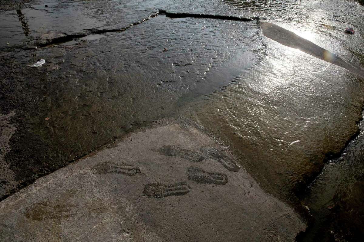 Footprints left by Alfonso Garcia shimmer in the morning sunlight. Garcia often sleeps in a drainage tunnel near Interstate 10. It often floods during heavy rains.