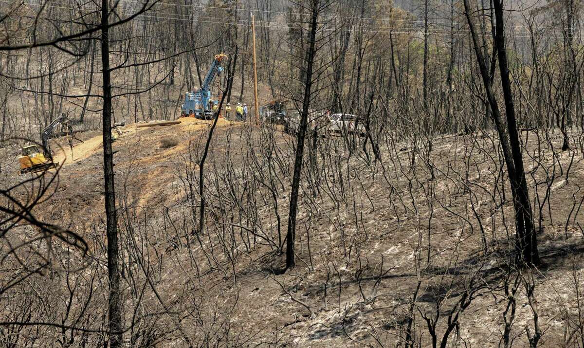 A PG&E utility crew works on power lines on a burned hillside during the Salt fire in the Gregory Creek area of Shasta County earlier this month. The utility now wants to bury 10,000 miles of its powerlines to avoid sparking new fires.