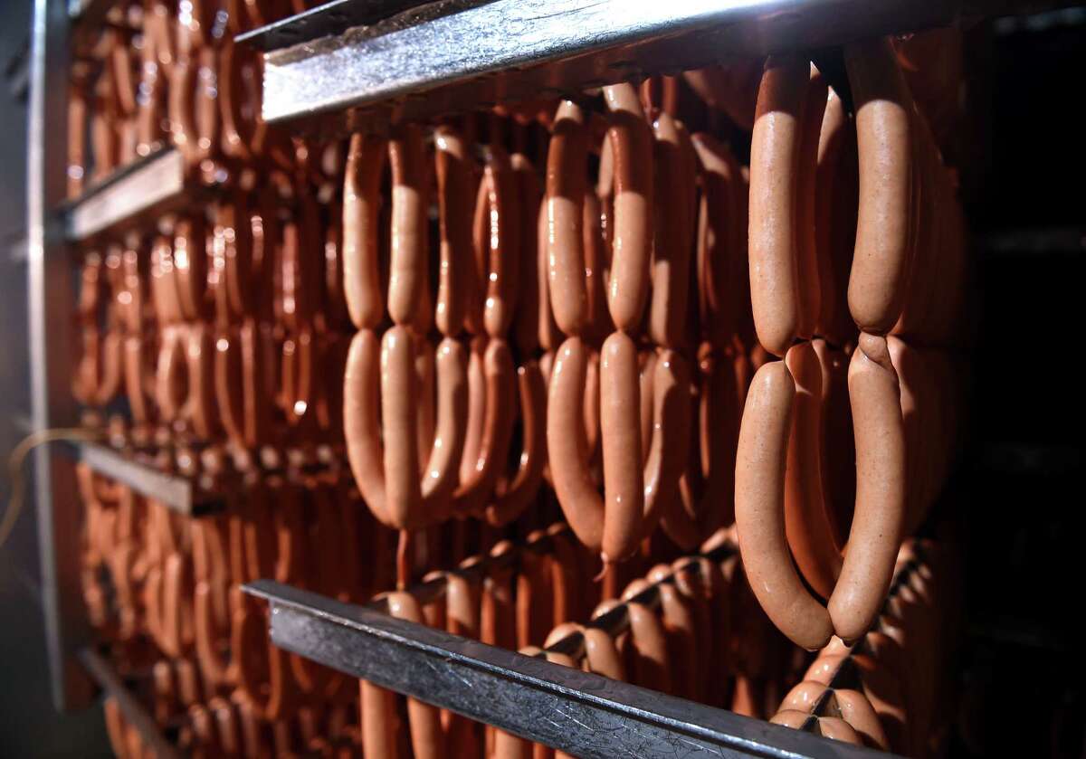 Racks of hot dogs hang in one of the smoke houses for hot dogs on National Hot Dog Day at the Hummel Bros. factory in New Haven on July 21, 2021.