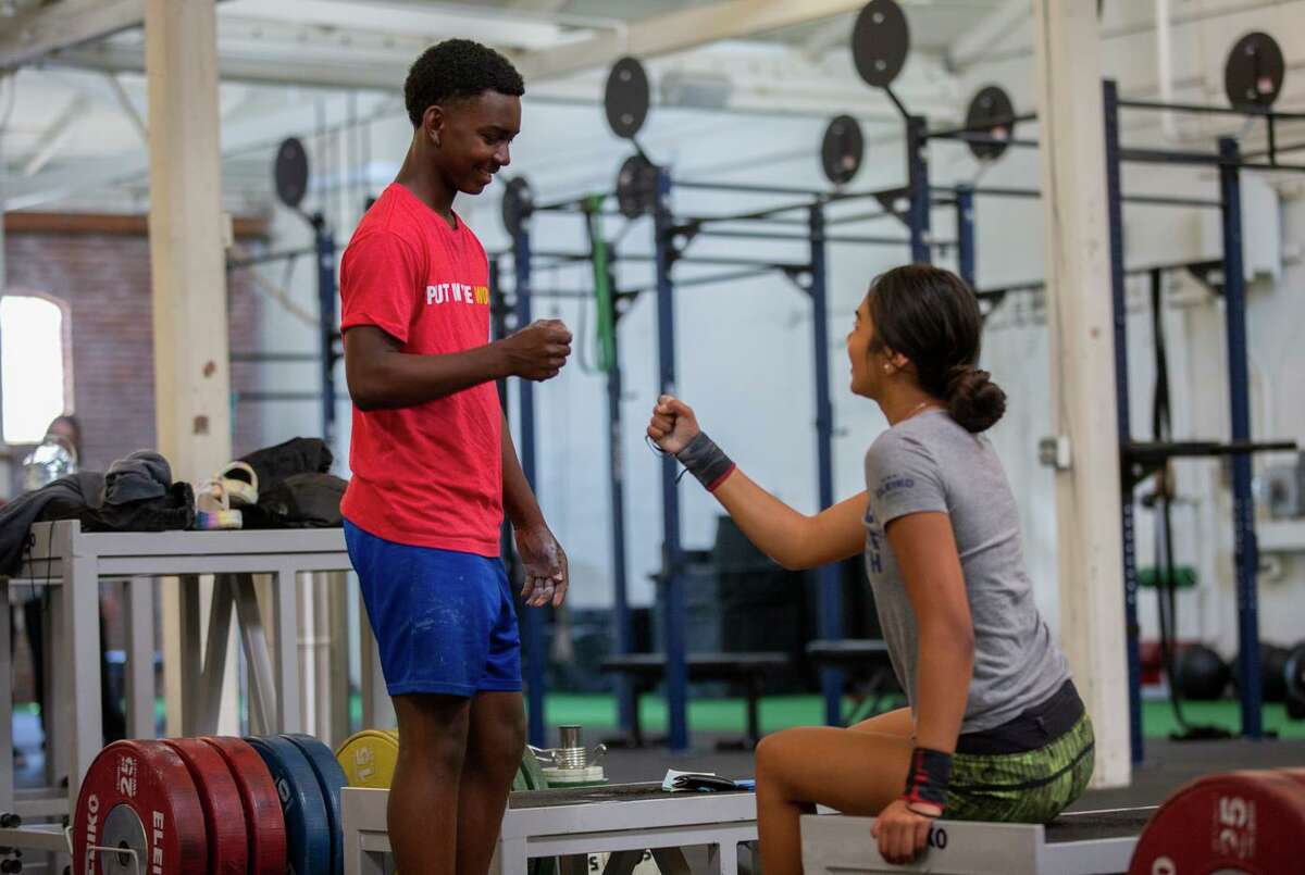 From left: Seth Evans and Annie Cabrera train at Speed Power Strength Gym, Wednesday, July 14, 2021, in Oakland, Calif. Evans is the U.S. champion in Olympic weightlifting in the 13-and-under group.