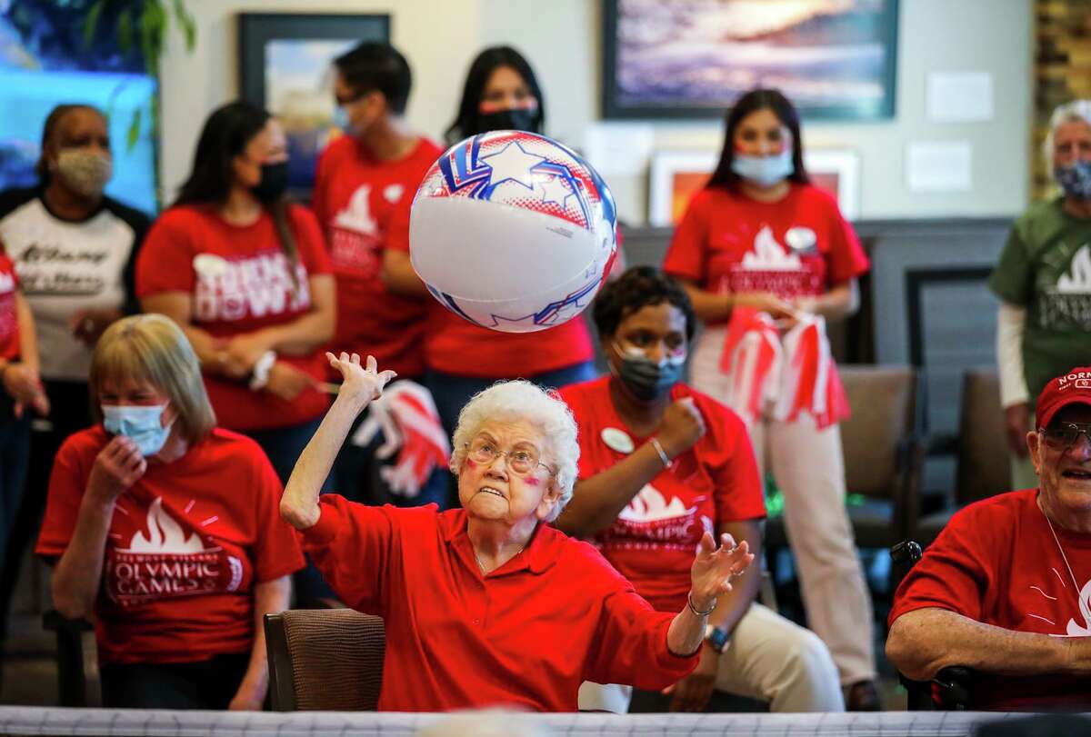 Belmont Village Sunnyvale resident Joyce Molyneaux tries to hit it between the chairs in a seated volleyball game.