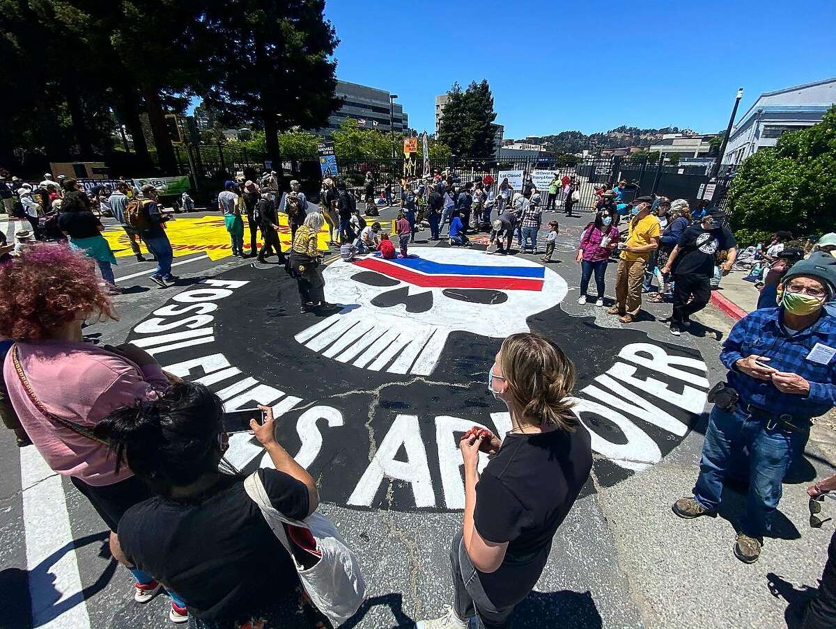 Community members gather around a street painting completed by attendants of the 8th annual Anti-Chevron Day at the Chevron oil refinery in Richmond, California on May 21, 2021.