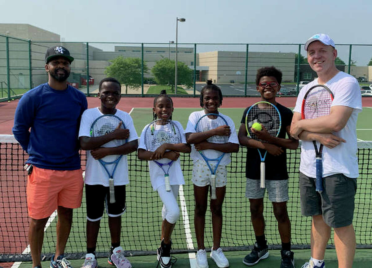 Members of Net Runners pose with Kweisi Kenyatte on one of the tennis courts at Liberty Middle School.
