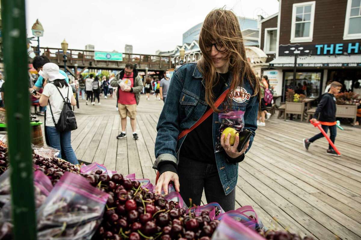 Becca Camping, a restaurant worker whose unemployment benefits were frozen after she was laid off last year due to the pandemic, shops for fruit at Fisherman’s Wharf in San Francisco.