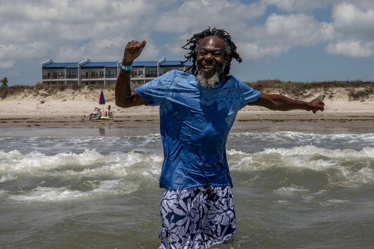 Neville punches the air with delight after being splashed by a large wave at the beach at Corpus Christi. Neville, who normally sleeps in boxes in a little nook downtown, was brought to Corpus Christi by a group of three homeless outreach workers to see if he could handle public transportation. The outreach workers are trying to reconnect him to his family in Zimbabwe.