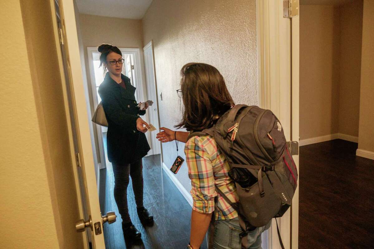 Anusha Datar, who recently moved to San Francisco from Boston, takes a card from Sadie Wing a real estate agent during an open house walk through in San Francisco.