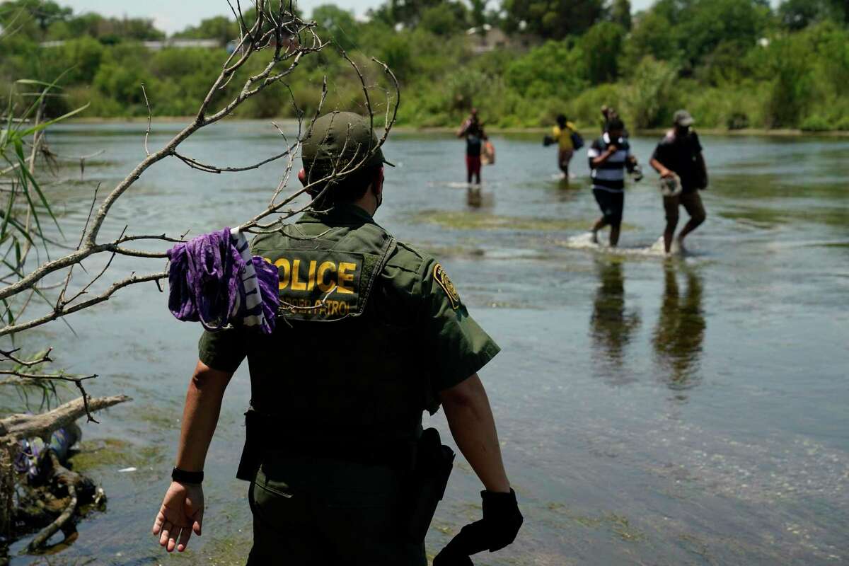 A Border Patrol agent watches as a group of migrants walk across the Rio Grande in June on their way to turning themselves in upon crossing the U.S.-Mexico border in Del Rio.