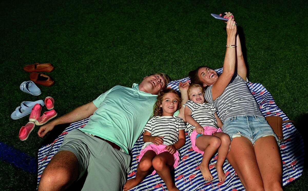 Brendan and Kate Noble and their children, Charlotte and Claire, 4 and 2, enjoy the Darien 2021 Fireworks Display at Darien High School Thursday, July 23, 2021, in Darien, Conn. Last year's display was cancelled due to the pandemic.