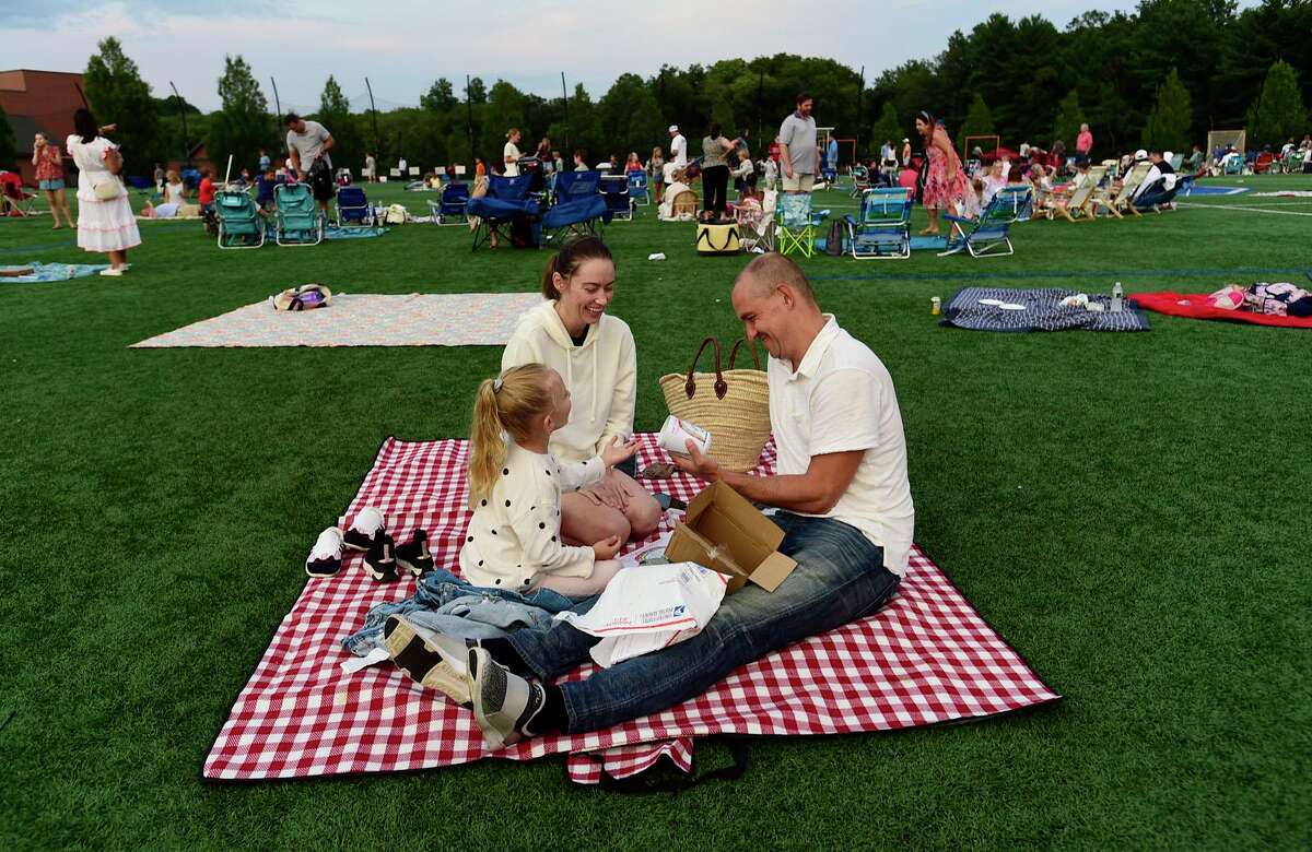 Residents Veronika and Jasper Rietmeijer and their daughter, Olivia, enjoy the Darien 2021 Fireworks Display at Darien High School Thursday, July 23, 2021, in Darien, Conn. Last year's display was cancelled due to the pandemic.