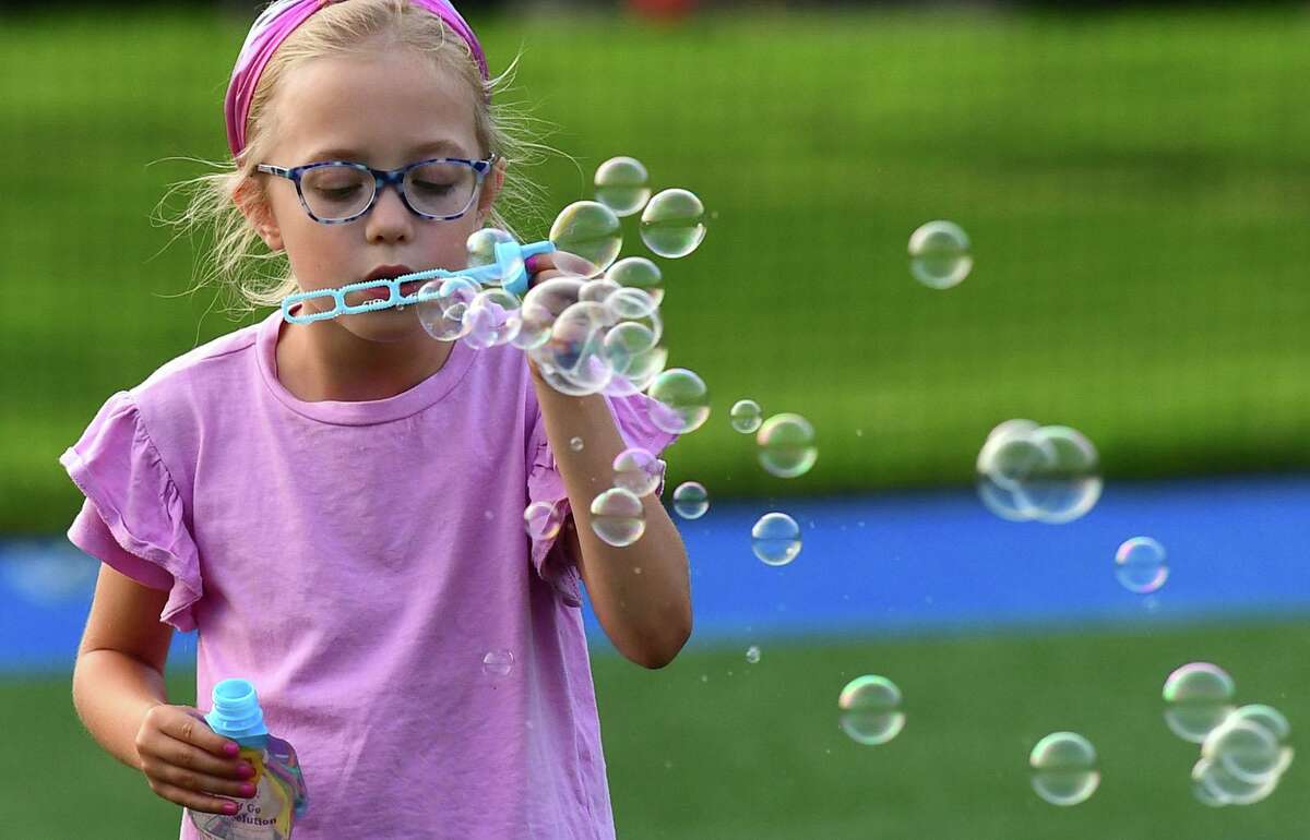Charlotte Yates, 6, blows bubble at the Darien 2021 Fireworks Display at Darien High School Thursday, July 23, 2021, in Darien, Conn. Last year's display was cancelled due to the pandemic.