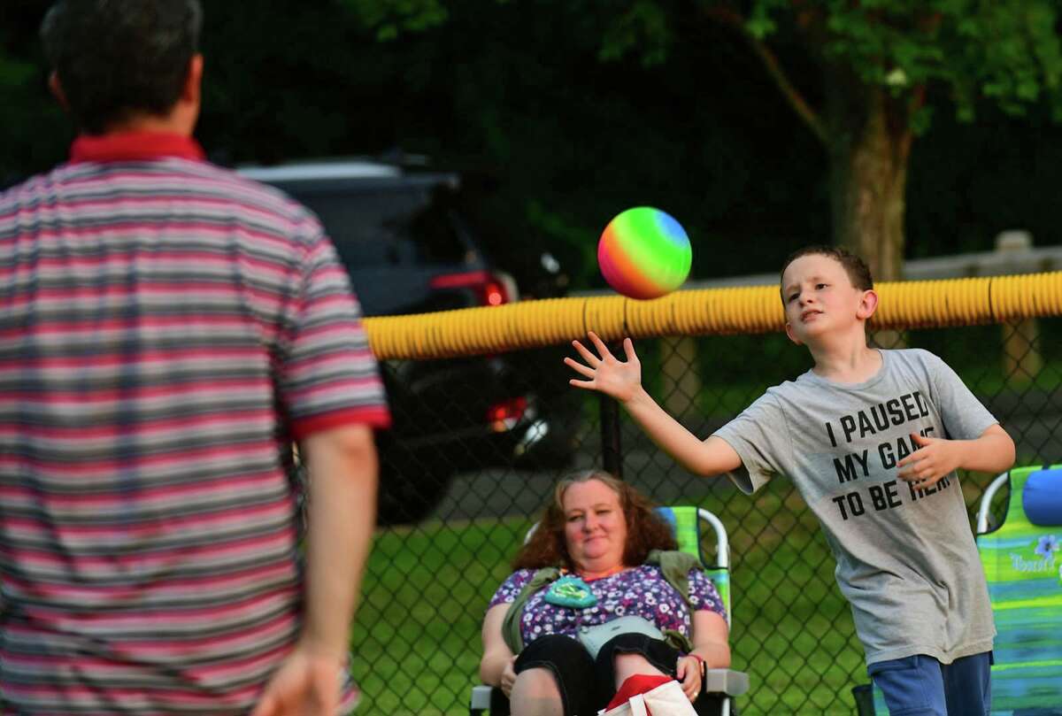 Jason Golden plays catch with his family at the Darien 2021 Fireworks Display at Darien High School Thursday, July 23, 2021, in Darien, Conn. Last year's display was cancelled due to the pandemic.