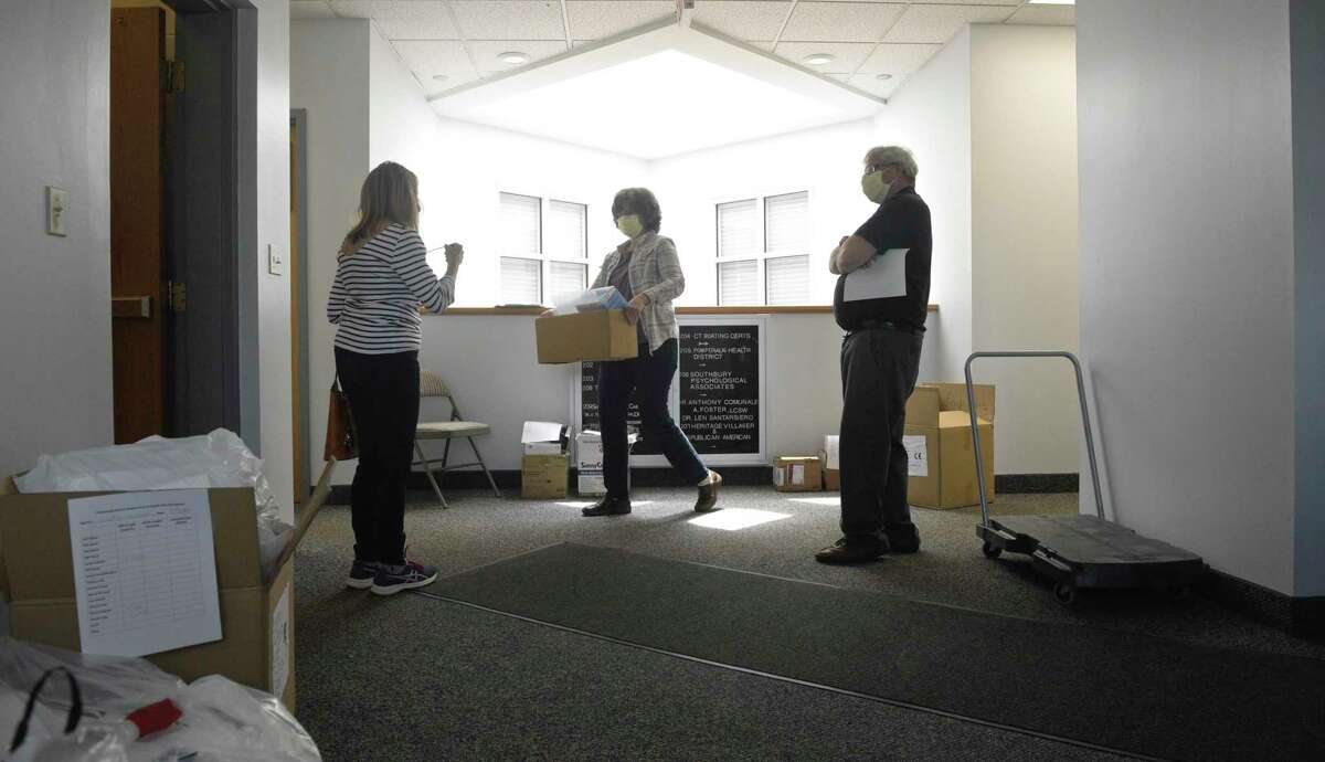 Mona LaBissoniere, health educator/sanitarian , and Neil Lustig, right, director, Pomperaug District Department of Health distribute PPE to Maureen Sallee, left, of Dr Sallee dentist office, at their office in Southbury, Conn. Thursday, April 7, 2020.