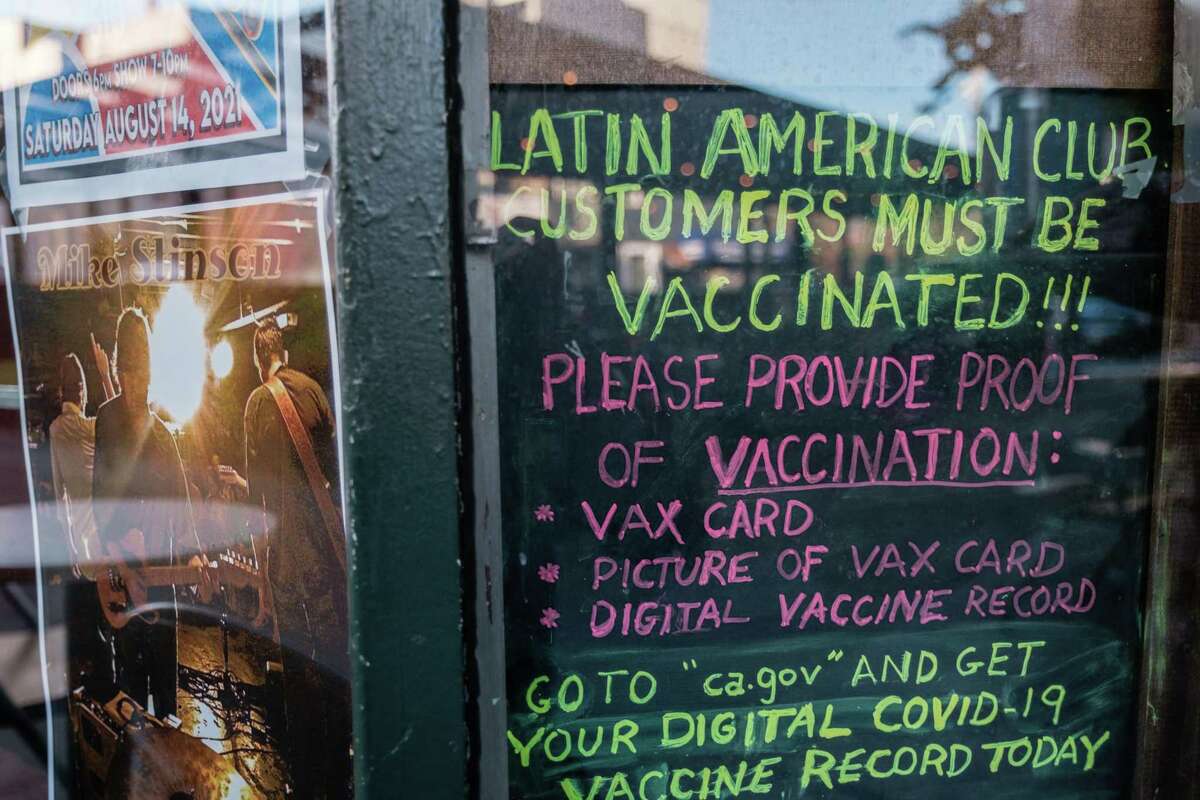 A sign asking all patrons to show proof of vaccination is seen in a window outside of the Latin America Club in San Francisco.