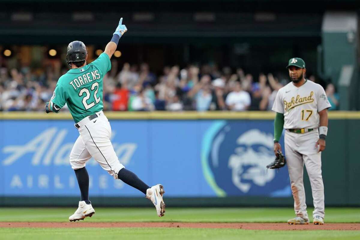Seattle Mariners' Luis Torrens (22) points as he runs the bases past Oakland Athletics shortstop Elvis Andrus (17) after hitting a solo home run during the second inning of a baseball game Friday, July 23, 2021, in Seattle. (AP Photo/Ted S. Warren)