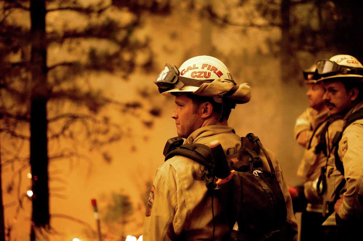 Firefighter Jesse Forbes monitors flames as his crew burns vegetation to stop the Dixie Fire from spreading near Prattville in Plumas County, Calif., on Friday, July 23, 2021.