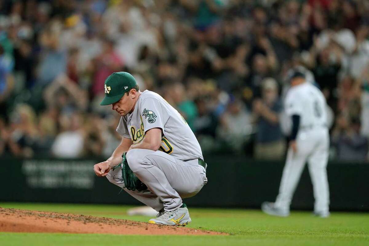 Oakland Athletics starting pitcher Chris Bassitt crouches by the mound after he gave up a two-run home run to Seattle Mariners' Mitch Haniger during the fifth inning of a baseball game Saturday, July 24, 2021, in Seattle. (AP Photo/Ted S. Warren)